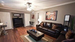 A modern living room with a leather sofa, a glass coffee table, and a flat-screen TV. - Hangout By Signature Vacation Rentals (Scottsdale)