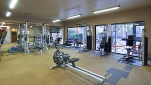 A gym with various exercise equipment, including treadmills, weight machines, and a rowing machine. - Hangout By Signature Vacation Rentals (Scottsdale)