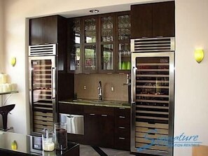 A modern kitchen with dark wood cabinets, stainless steel appliances, and a glass backsplash. - Grayhawk Condo By Signature Vacation Rentals (Scottsdale)