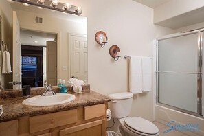 A bathroom with a sink, mirror, vanity, toilet, and shower.