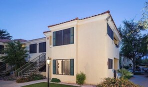 Un edificio de dos plantas con techo plano, ventanas amplias y una escalera que conduce a la entrada.