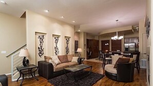 Ein geräumiges Wohnzimmer mit einer Couch, einem Couchtisch und dekorativen Wandbildern.