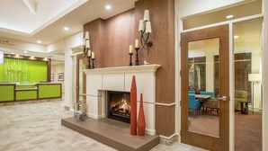 A lobby with a fireplace, a reception desk, and a seating area. - Hilton Garden Inn Olympia (Olympia)