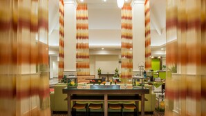 A modern hotel lobby with a central reception desk, seating area, and a staircase leading to an upper floor. - Hilton Garden Inn Olympia (Olympia)