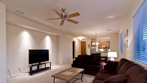 Ein Wohnzimmer mit Flachbildfernseher, Deckenventilator, Sofa und Couchtisch.