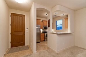 A kitchen with wooden cabinets, stainless steel appliances, and a window with blinds. - Fountain Sanctuary By Signature Vacation Rentals (Fountain Hills)