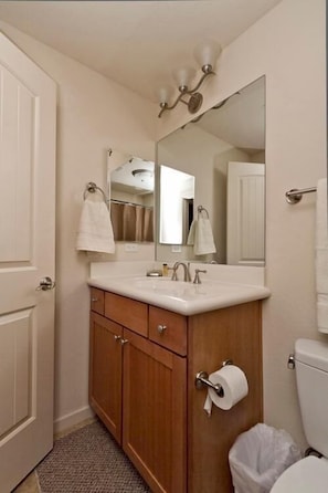 Een badkamer met een houten wastafelmeubel, een wastafel, een spiegel en een toilet.