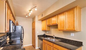 A kitchen with wooden cabinets, a black countertop, a stainless steel refrigerator, a dishwasher, and a gas stove. - Exclusively Yours By Signature Vacation Rentals (Scottsdale)