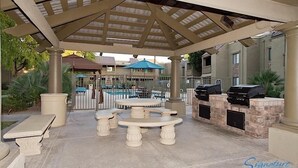 An outdoor patio area with a pool, a covered seating area, and barbecue grills. - Exclusively Yours By Signature Vacation Rentals (Scottsdale)