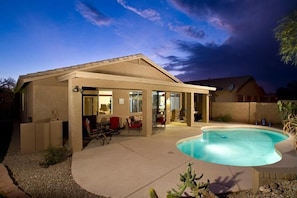 A house with a covered patio, a swimming pool, and outdoor furniture.