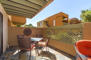 An outdoor patio with a table and chairs, a decorative wall, and a view of adjacent buildings.
