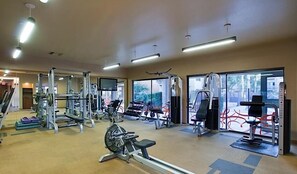 A gym with various exercise equipment, large windows, and a view of the outside. - Endless Summer By Signature Vacation Rentals (Scottsdale)