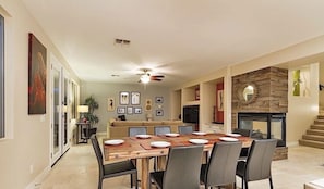A dining area with a wooden table set for six, a sofa, and a fireplace.