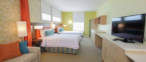 Habitación de hotel con dos camas, un sofá, un televisor y un escritorio.