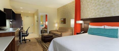 Une chambre d’hôtel comprenant un lit, un bureau, une chaise, un canapé et un téléviseur.