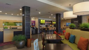 A modern hotel lobby with a reception desk, seating areas, and a coffee bar. - Home2 Suites by Hilton Portland (Portland)