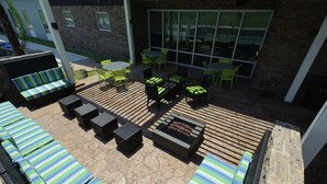 An outdoor patio with striped lounge chairs, a fire pit, and green chairs. - Home2 Suites by Hilton Portland (Portland)