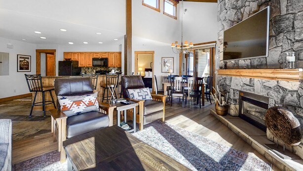 A spacious living room with a stone fireplace, leather furniture, and a large TV. - The Lodge at Steamboat (Steamboat Springs)