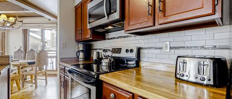A kitchen with wooden cabinets, a microwave, a stove, and a toaster.