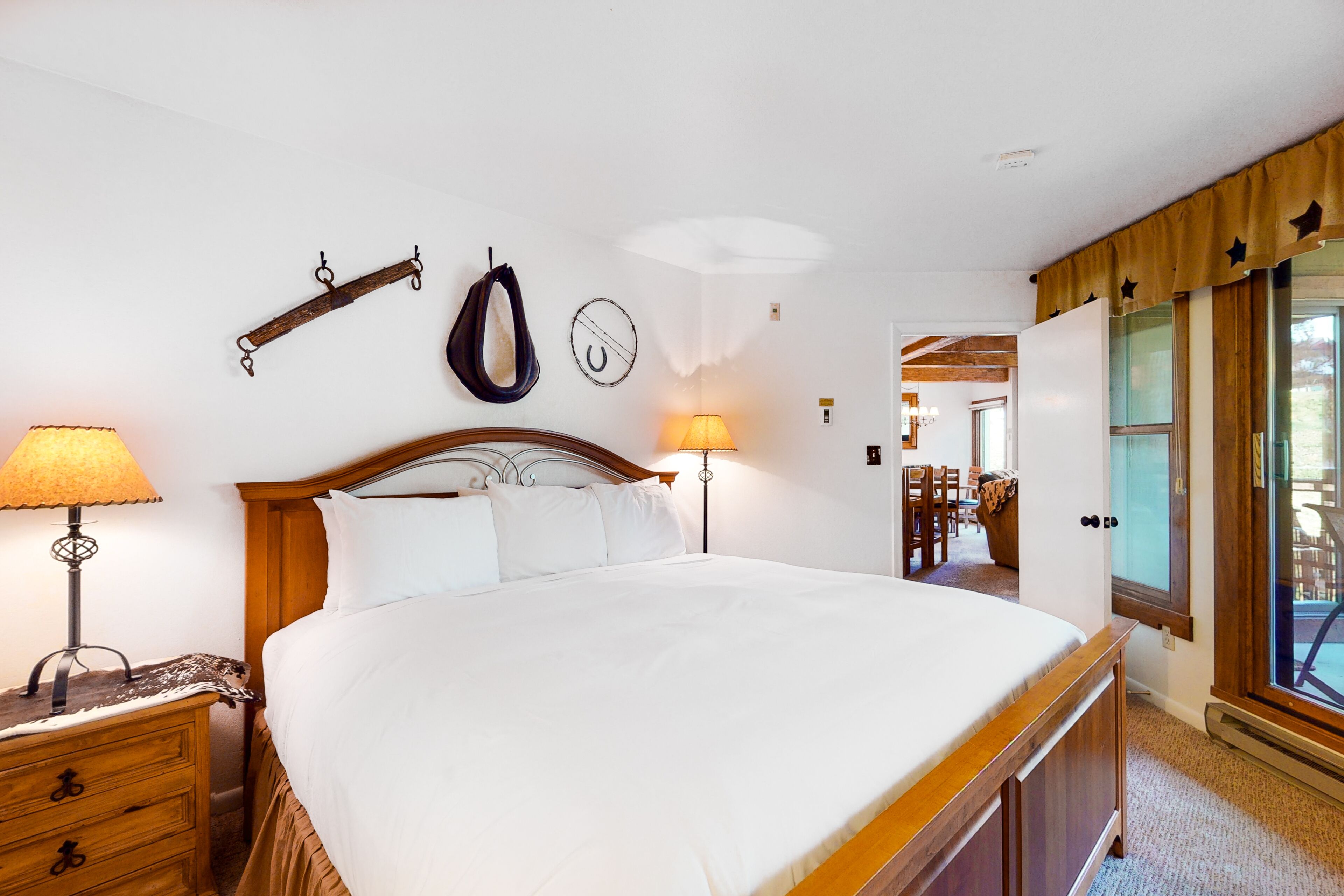 A neatly arranged bedroom with a large bed, two bedside lamps, a wooden nightstand, and a wall-mounted coat rack.