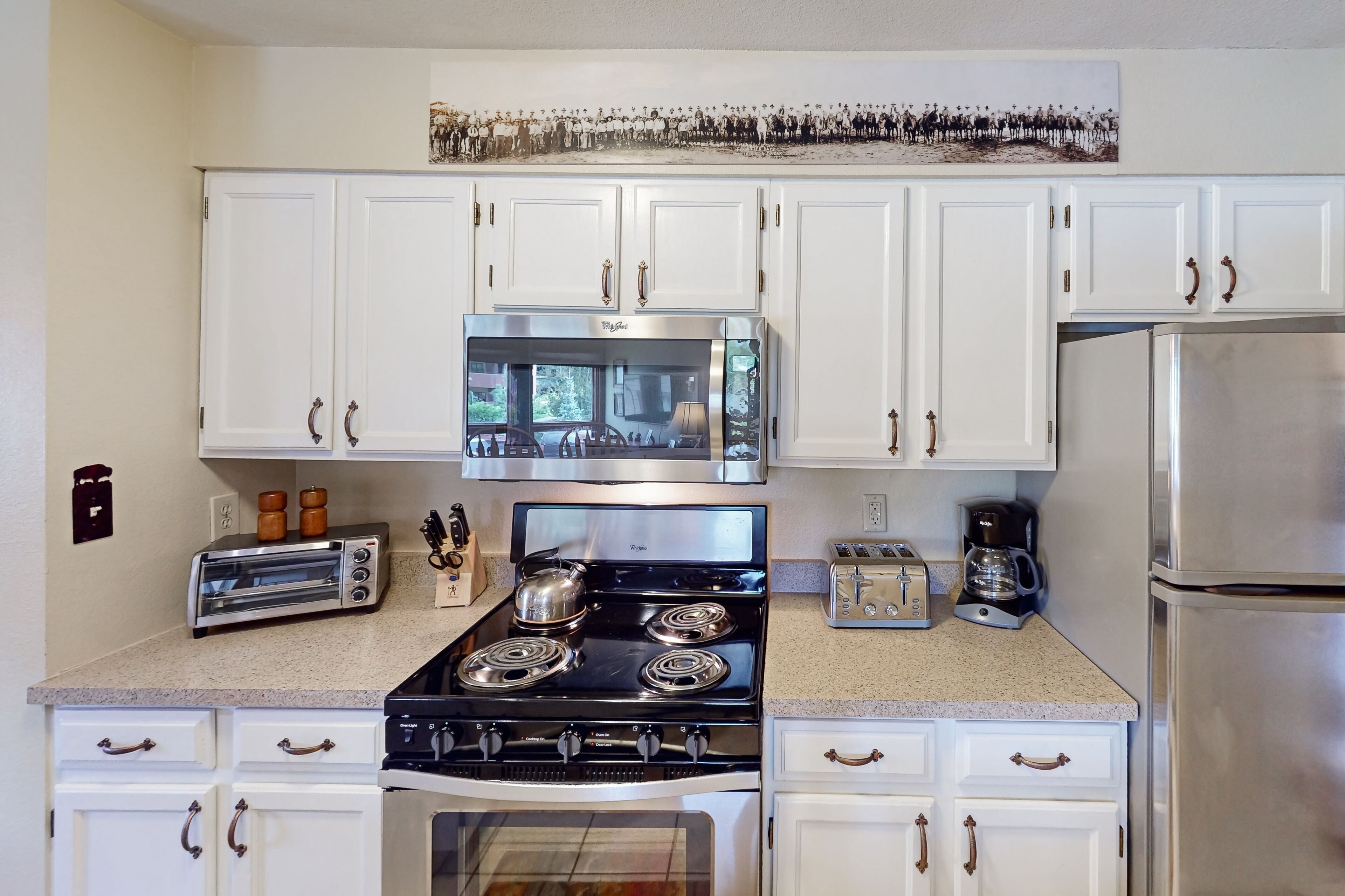 A kitchen with white cabinets, a stainless steel stove, and a refrigerator.