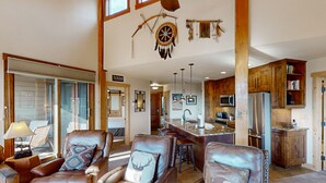 A spacious living room with leather chairs, a large window, and a view of the kitchen. - The Lodge at Steamboat (Steamboat Springs)