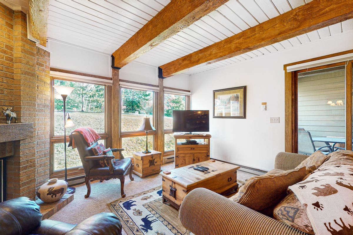 Ein gemütliches Wohnzimmer mit Kamin, Ledersofa, Holztisch und Fernseher.