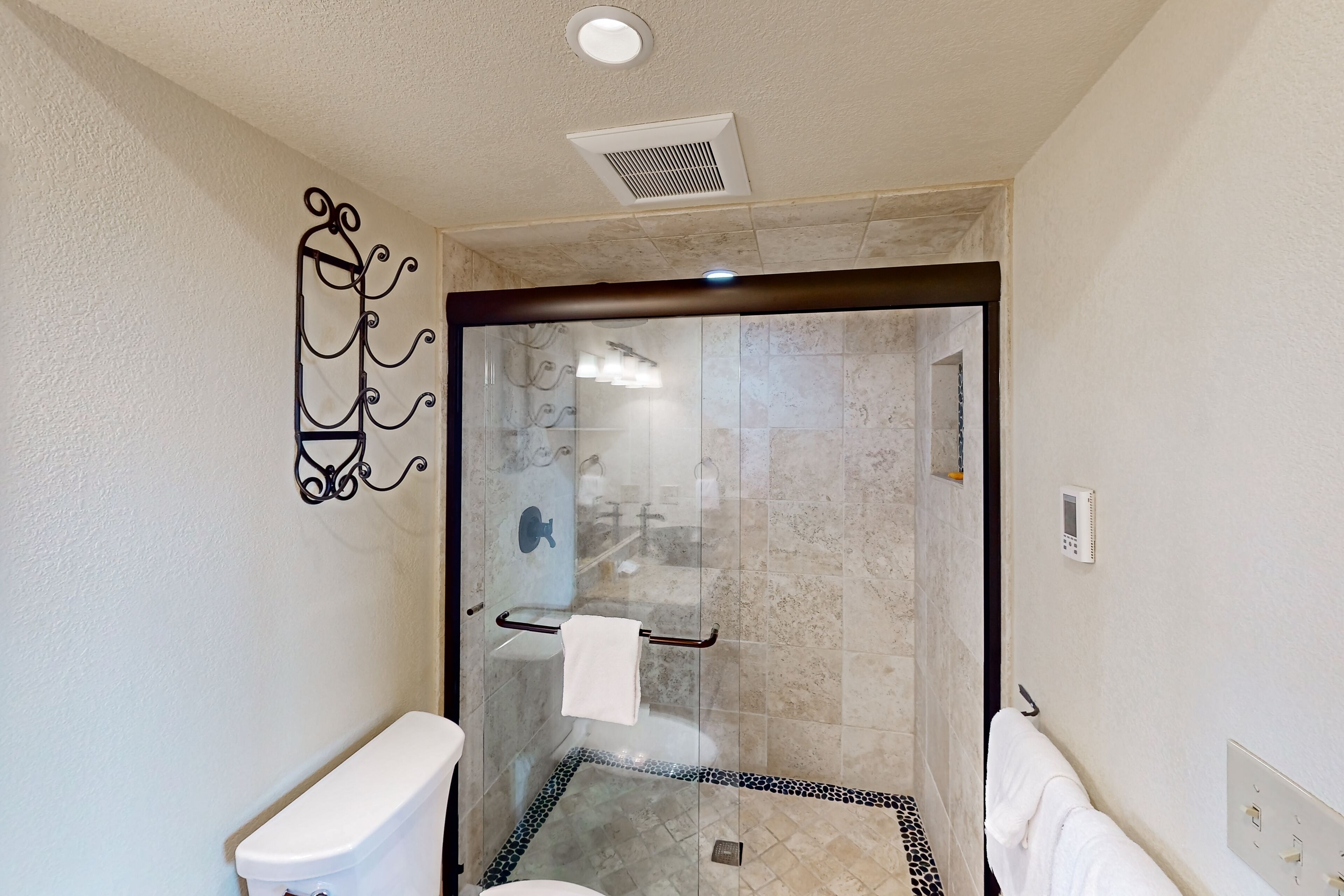 A modern bathroom with a glass-enclosed shower, a toilet, and a towel rack.