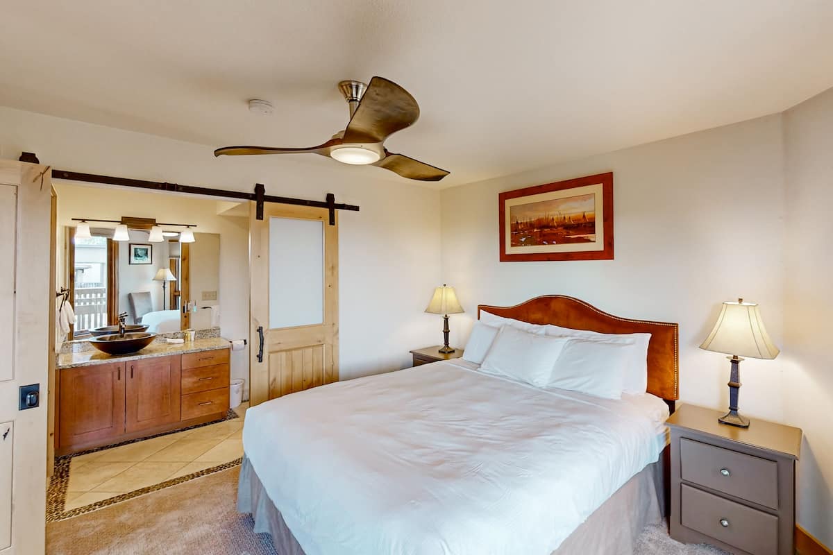 Ein Hotelzimmer mit Bett, Nachttisch, Lampe und Deckenventilator.