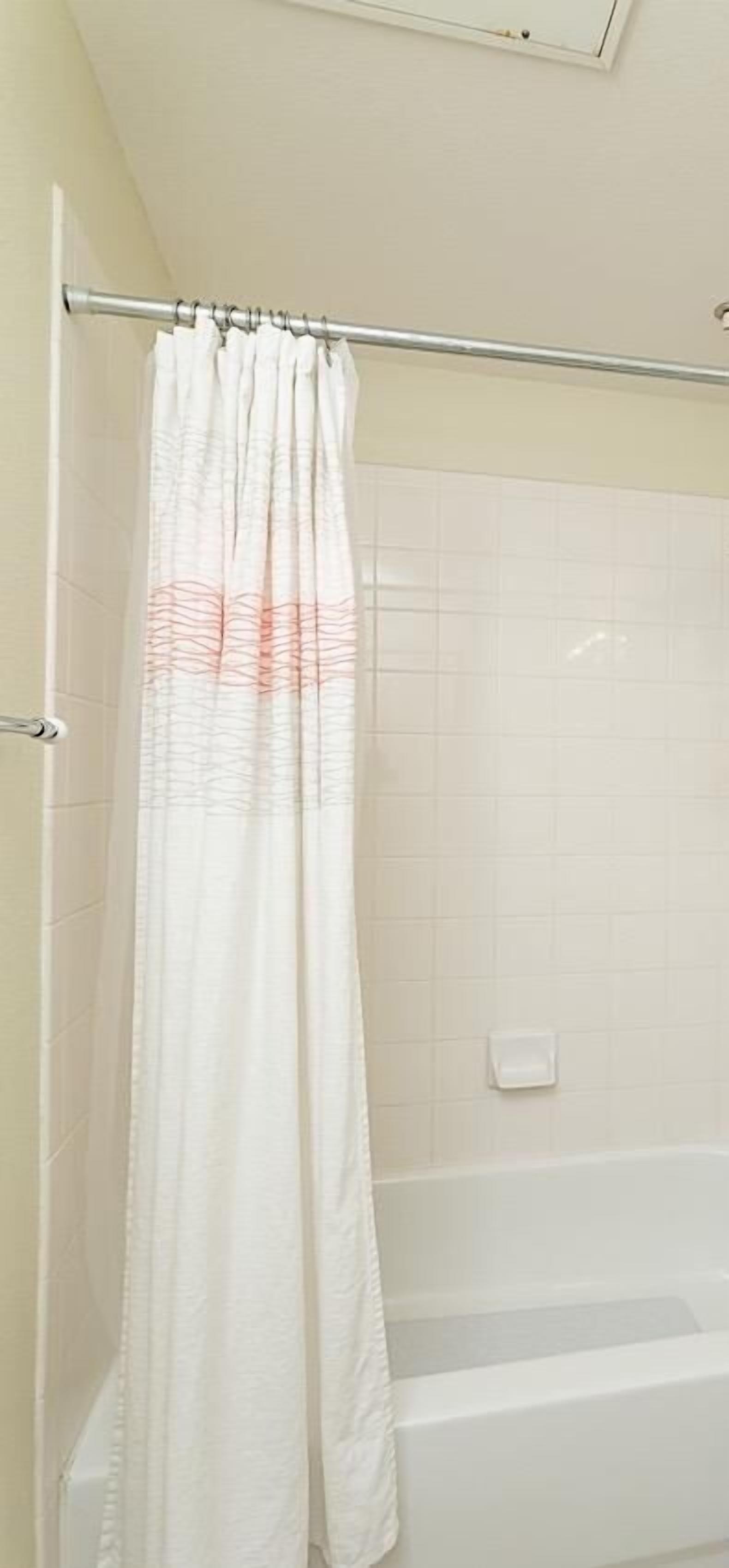 A bathroom with a shower curtain, tiled walls, and a bathtub.