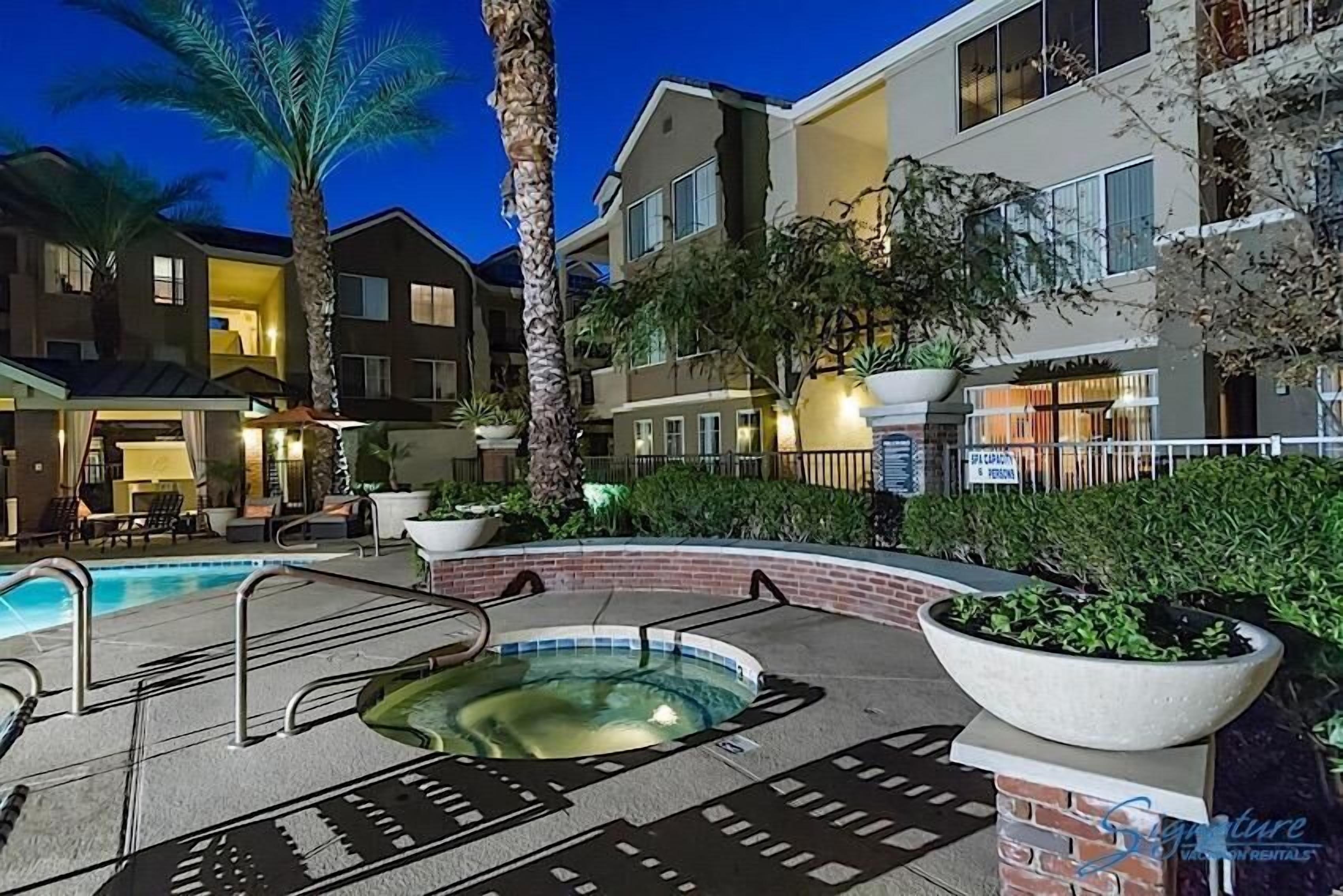 A hotel courtyard with a swimming pool, palm trees, and a spa area.