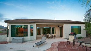 Et moderne hus med en patio, swimmingpool, liggestole og grill.