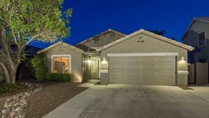 A residential house with a garage, a driveway, and a well-maintained lawn. - Western Belle By Signature Vacation Rentals (Surprise)