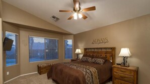 A bedroom with a bed, two nightstands, a ceiling fan, and a wall with a motivational quote. - Western Belle By Signature Vacation Rentals (Surprise)
