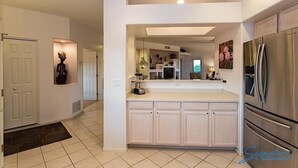 A modern kitchen with white cabinetry, a stainless steel refrigerator, and a built-in island with a sink and countertop.