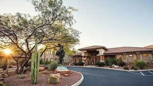 A building with a tiled roof, a cactus garden, and a statue.