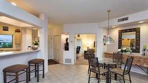 A modern kitchen with a dining area, featuring a large island, bar stools, and a chandelier.