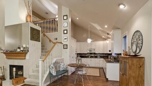 A spacious kitchen with white cabinets, a wooden dining table, and a staircase with a railing. - Velvet Dream By Signature Vacation Rentals (Tempe)