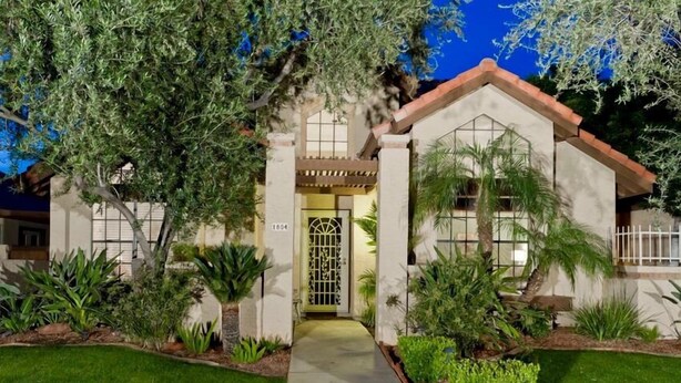 A two-story house with a front entrance, a garage, and a well-maintained garden with various plants and a pathway leading to the door. - Velvet Dream By Signature Vacation Rentals (Tempe)
