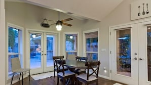 A dining area with a round table and chairs, a ceiling fan, and a view through glass doors. - Velvet Dream By Signature Vacation Rentals (Tempe)