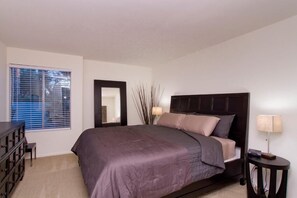 A bedroom with a large bed, a dresser, a mirror, and a bedside table with a lamp. - Ultra Chic and Modern By Signature Vacation Rentals (Scottsdale)