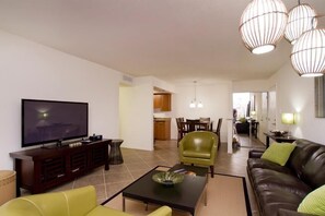 A modern living room with a flat-screen TV, leather sofa, and a dining area with a table and chairs. - Ultra Chic and Modern By Signature Vacation Rentals (Scottsdale)