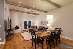 A spacious living room with a wooden dining table, dark chairs, a sofa, and a television. - Truly Charming at McCormick Ranch By Signature Vacation Rent (Scottsdale)