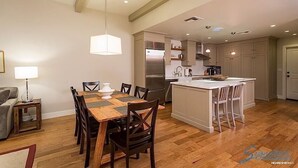 Cozinha moderna com ilha central, mesa de jantar de madeira e cadeiras.