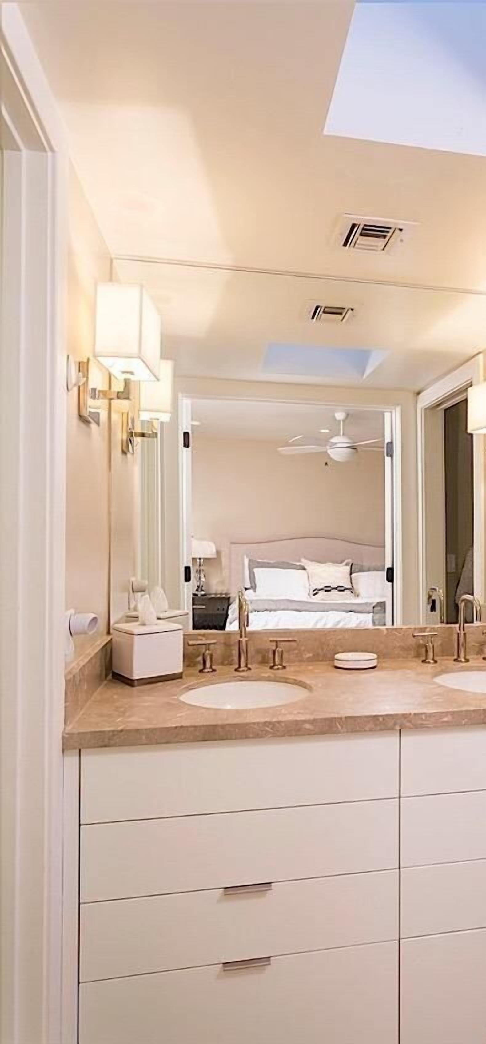 A modern bathroom with a double sink, vanity, and a ceiling fan.