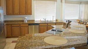 A kitchen with granite countertops, wooden cabinets, a dishwasher, and a window with blinds. - Troon Skyline Private By Signature Vacation Rental (Scottsdale)