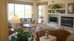 A living room with a fireplace, a television, and a ceiling fan. - Troon Skyline Private By Signature Vacation Rental (Scottsdale)