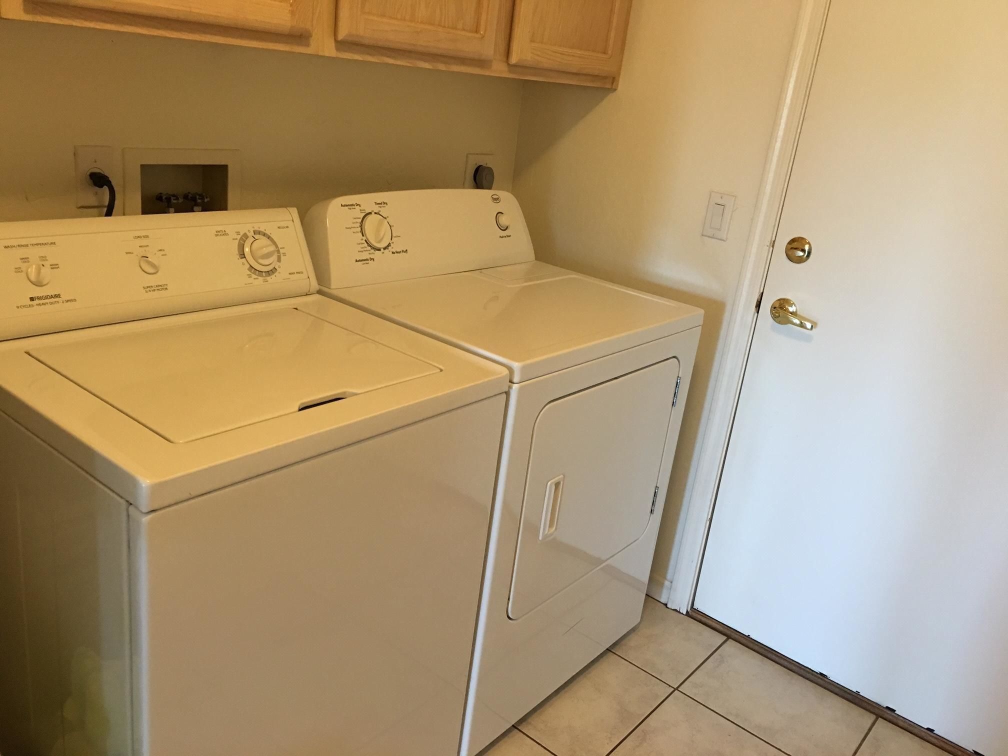 A laundry room with two front-loading washing machines and a dryer.