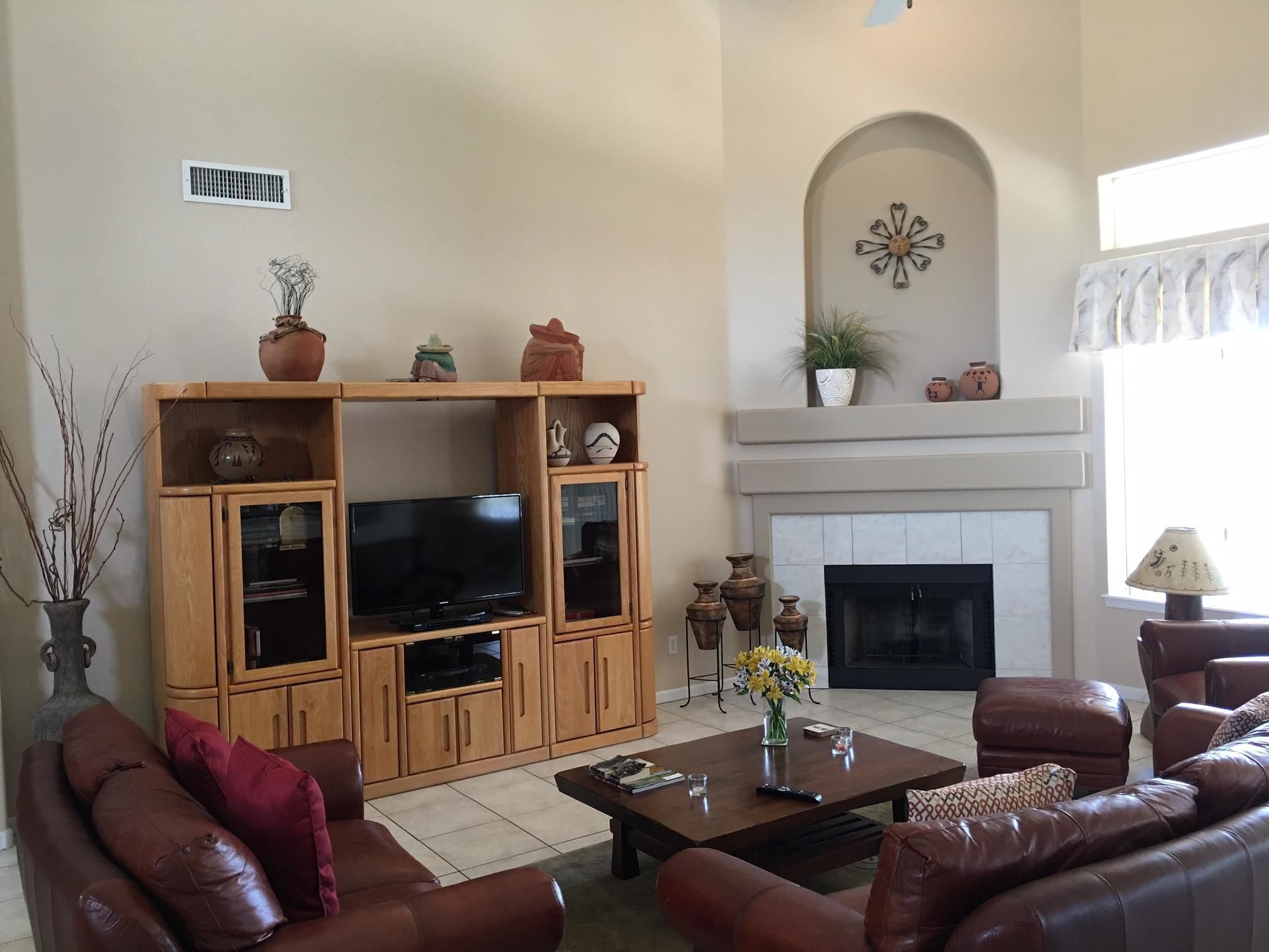 A living room with a fireplace, wooden entertainment center, leather sofas, and a coffee table.