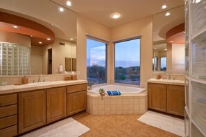 A modern bathroom with a large bathtub, double sinks, and a large mirror.